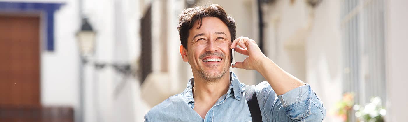 A young man walking down the street on his phone and contemplating what to do when you lose your job 