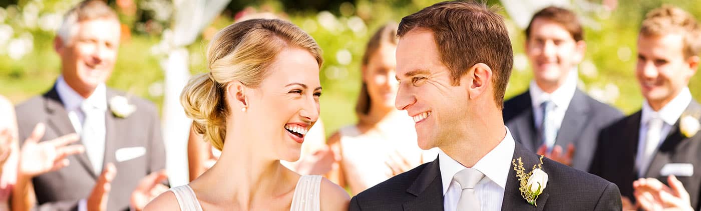 bride and groom smile at each other as they walk down the aisle and reflect on marriage and finances