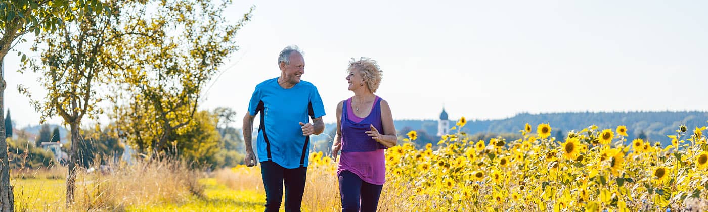 Couple jogging by a sunflower field, discussing a deferred annuity 