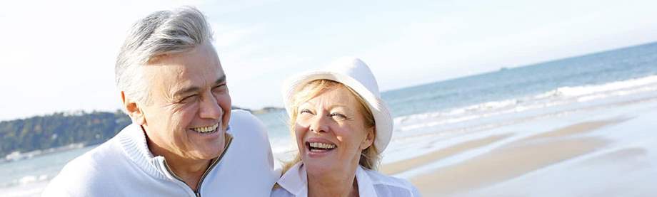 couple laughs and walks on the beach and discusses the question: how much do I need to retire at 62