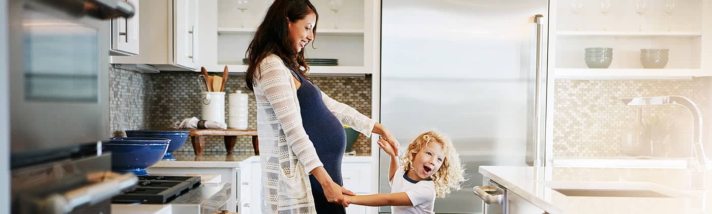 Expecting mother dancing with child in kitchen