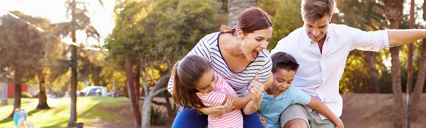 young family of four plays soccer in the park as parents think about benefits of roth ira conversions