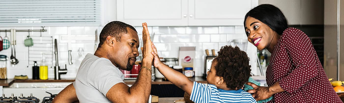 Father high-fives his son while mother watches after parents discuss their annuity options. 