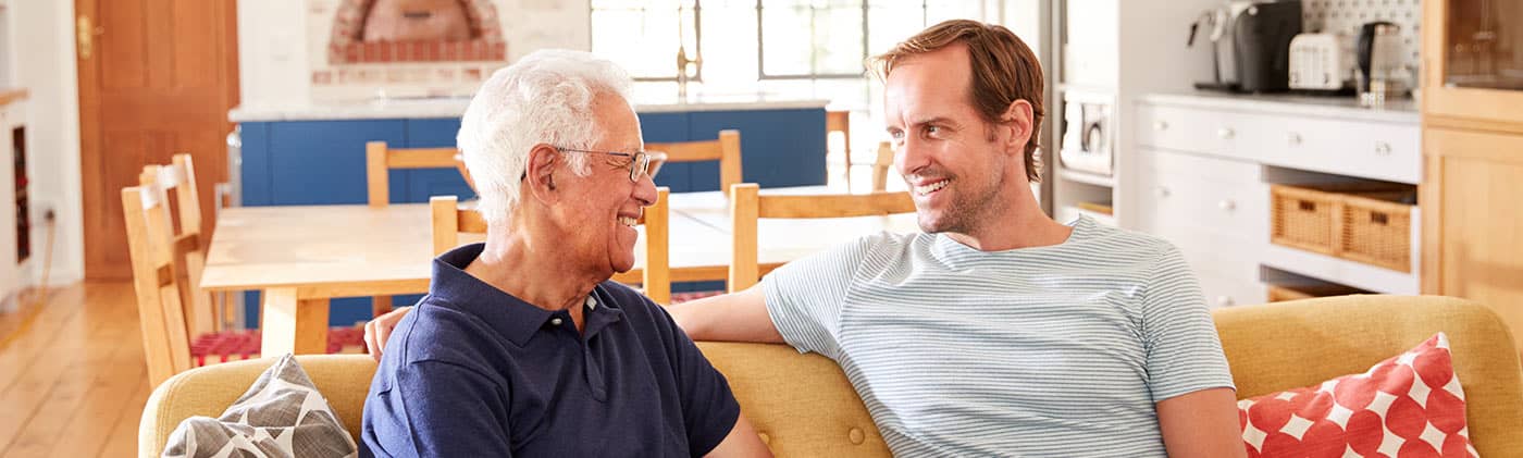 mature father and adult son on a park bench cheerfully discuss how to choose a fixed indexed annuity