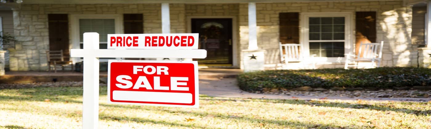 House with For Sale sign that says priced reduced