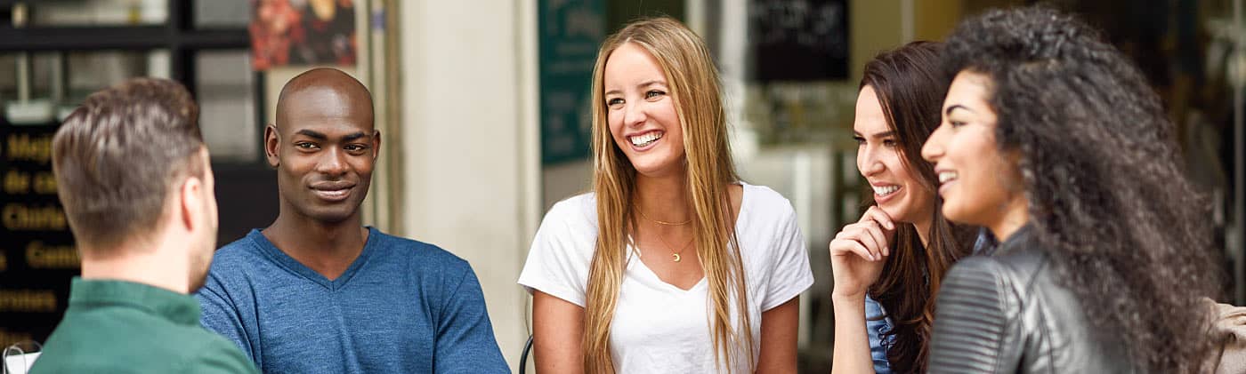 Friends sit together at a cafe discussing life insurance for young adults 