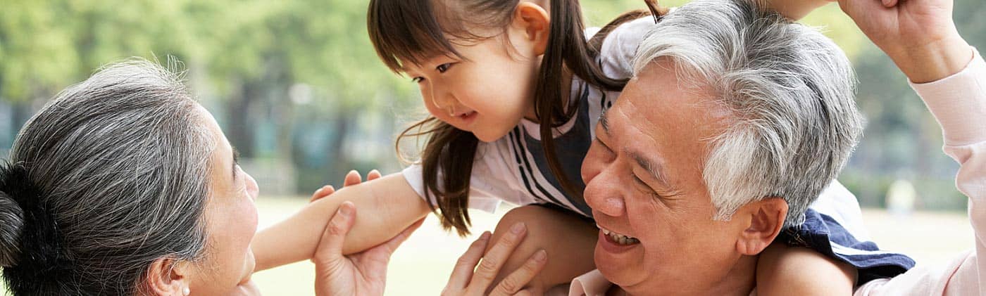 grandparents play with their grandchild in a park saving for retirement