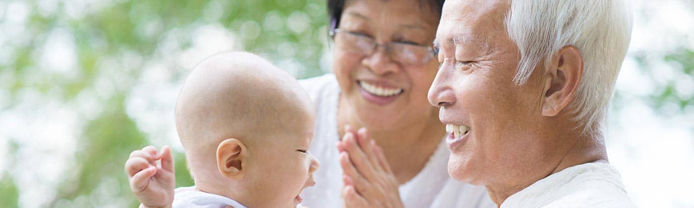 Grandparents play with young grandchild outdoors: types of life insurance