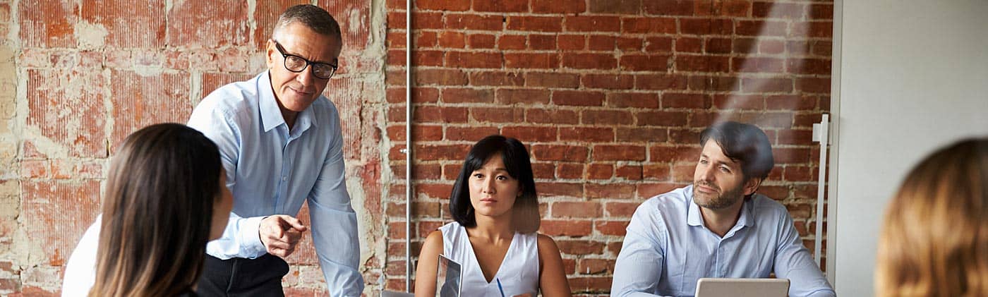 group of employees headed by an older businessman in a planning meeting business protection