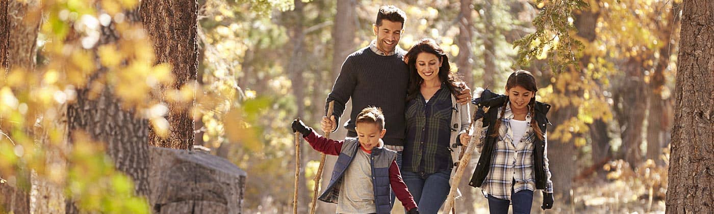 parents think about 10-year term life insurance as they walk in the woods with their daughter and son