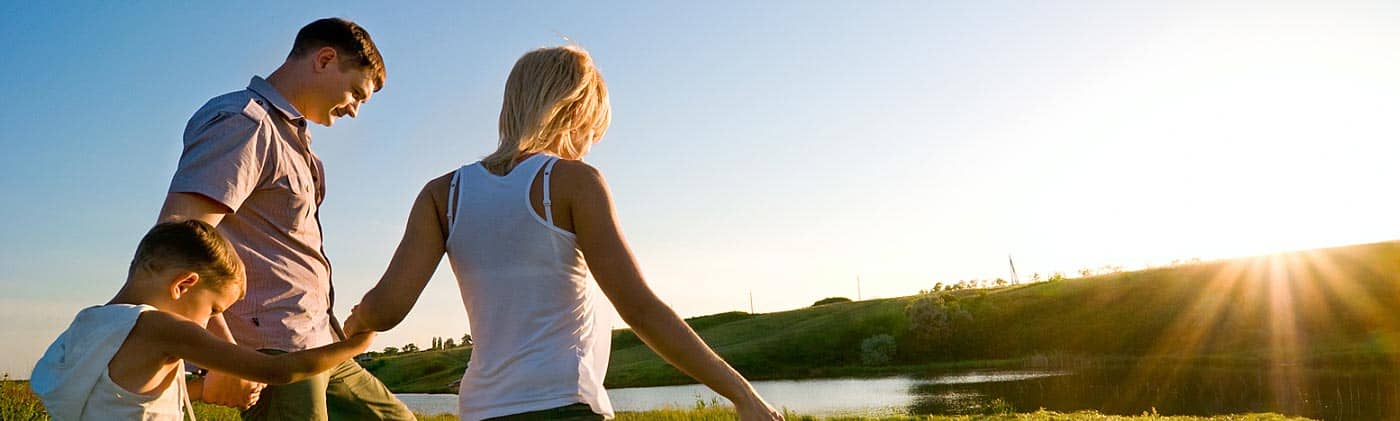 happy family walking through a green field toward sunset 15 year term life insurance
