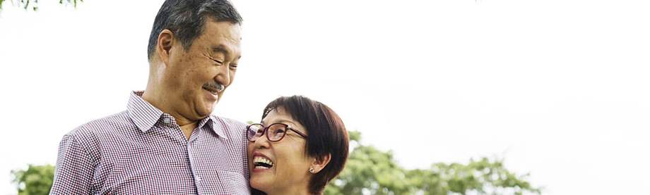 happy mature husband and wife embrace in the park as they discuss options for buying life insurance