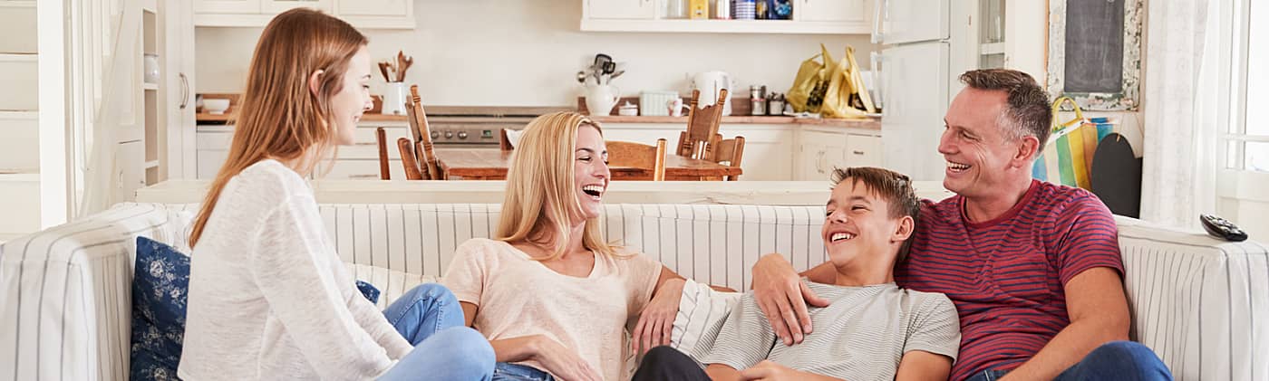 happy mother, father, son and daughter discuss managing family finances on the couch at home