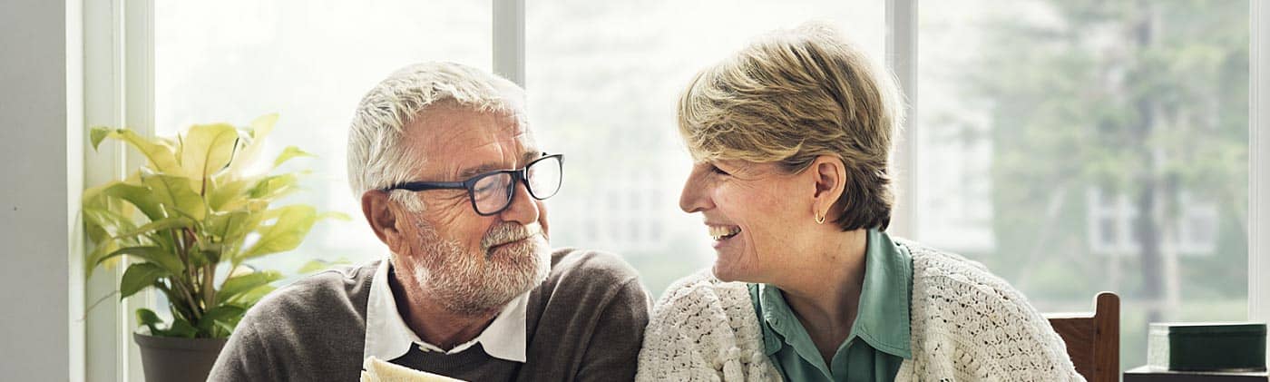 happy older couple eating a meal together: when to start saving for retirement