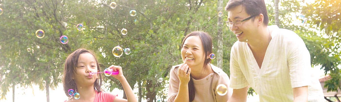 happy parents playing with their daughter in the park on a sunny day do I need life insurance?