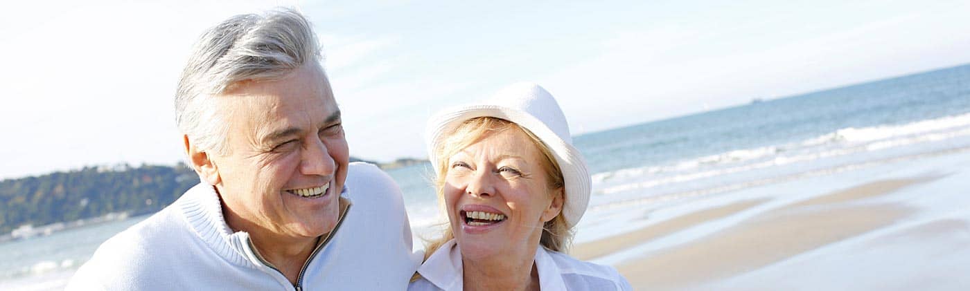happy senior couple walking along the beach save for retirement