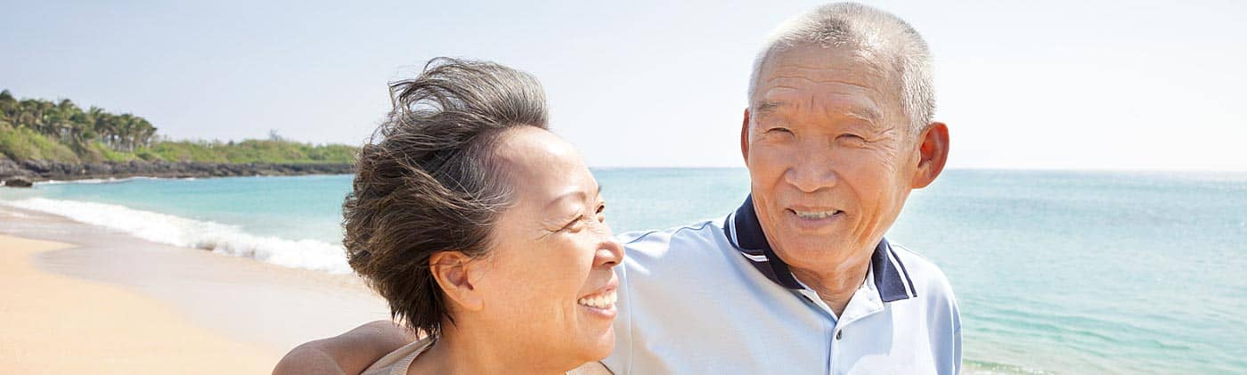 happy senior couple walks along the beach costs in retirement