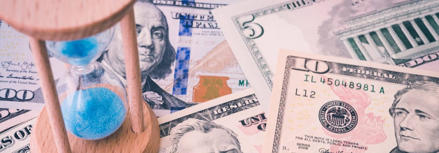 Hourglass on US dollar banknote background. Concept world economic of time to consider raise or reduce interest rate via FED.