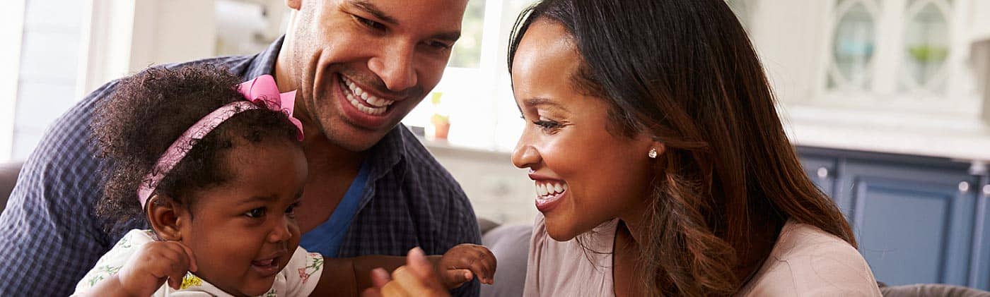 husband and wife playing with their infant daughter on the couch 20 year term life insurance