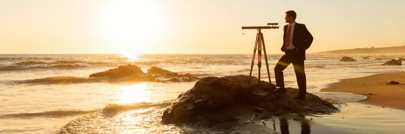 Businessman looks at the horizon through a telescope.