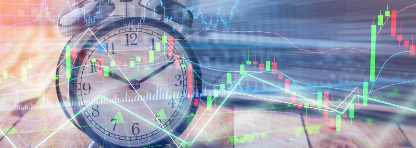 Clock alarm with stock graph chart in laptop screen background.