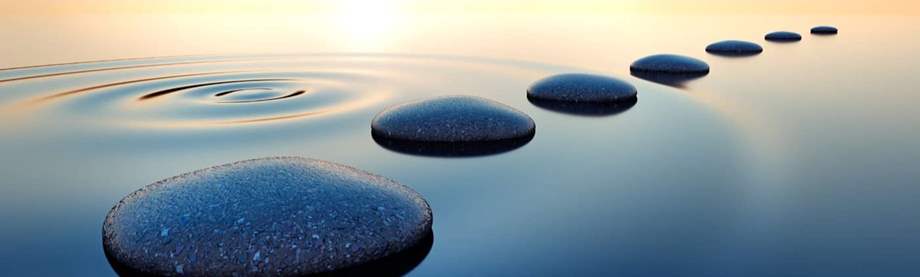 Stones in calm water with evening sun with horizon. Tranquil scenery.