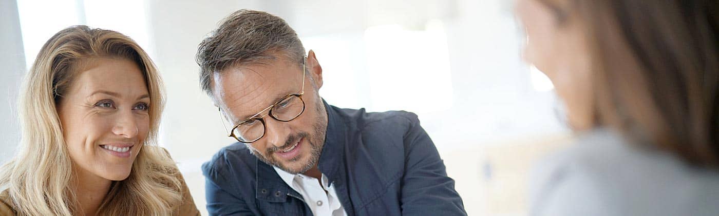 mature couple looking over statements with a financial advisor investment education
