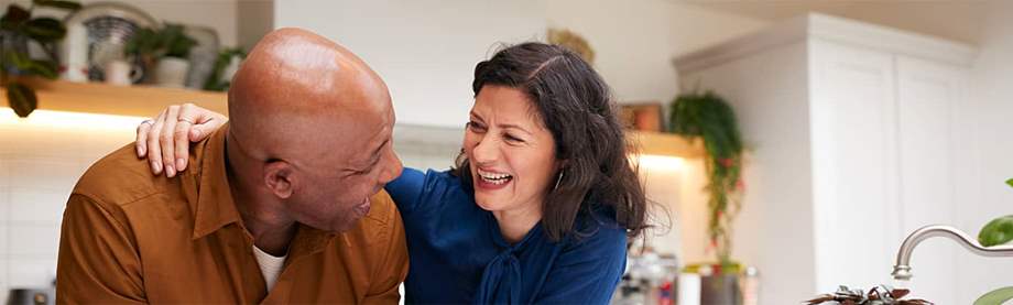 A couple leans on their kitchen counter discussing "how much should I save for retirement?" 