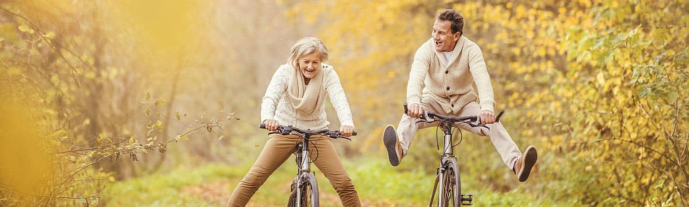 mature couple rides bikes in the woods and discusses choosing a single premium immediate annuity