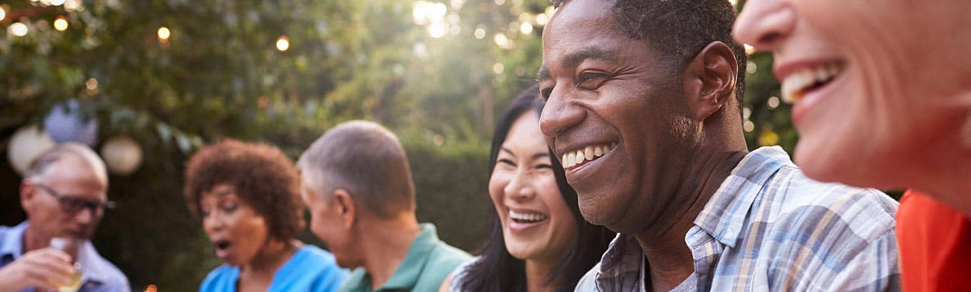 Mature friends enjoy a backyard dinner party in the summer: life after retirement