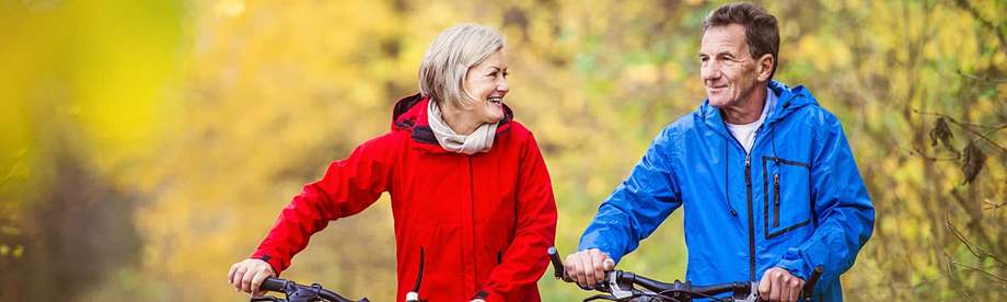 Middle-aged couple riding bikes and talking about whether to get a death benefit rider 