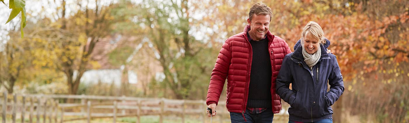 Middle-aged couple who share a spousal IRA walking their dog on a fall day 