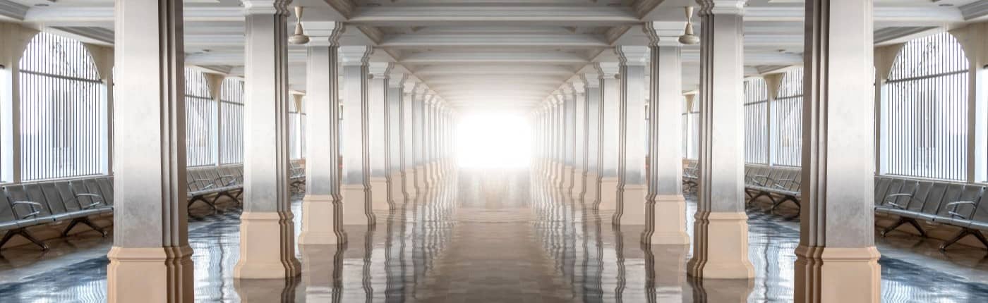 Symmetrical columned corridor fading to light.