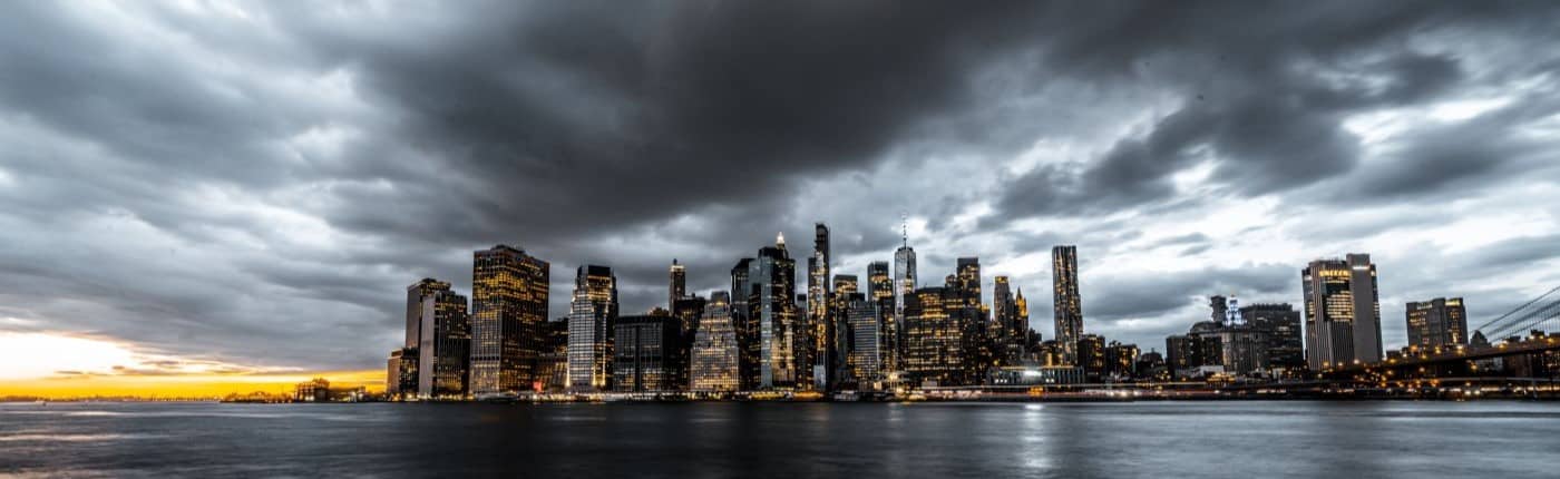 Manhattan cityscape captured with long exposure under a dramatic, stormy sky.