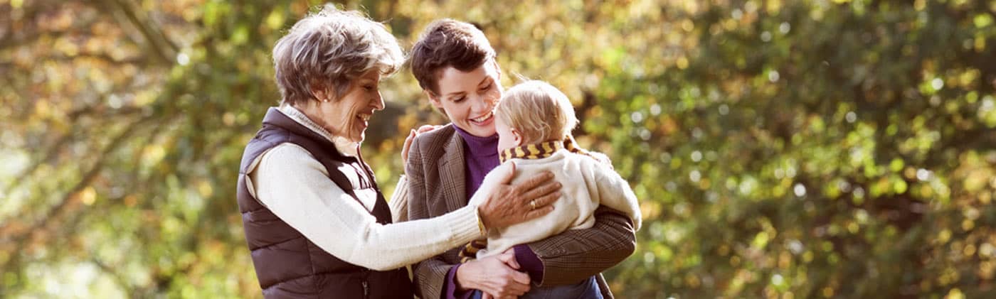 Mother and grandmother holding a baby outside and talking about what a spendthrift trust is 