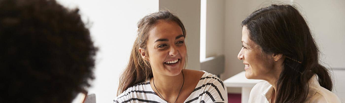 mother talks to her daughter about college graduate finances with a financial planner in an office