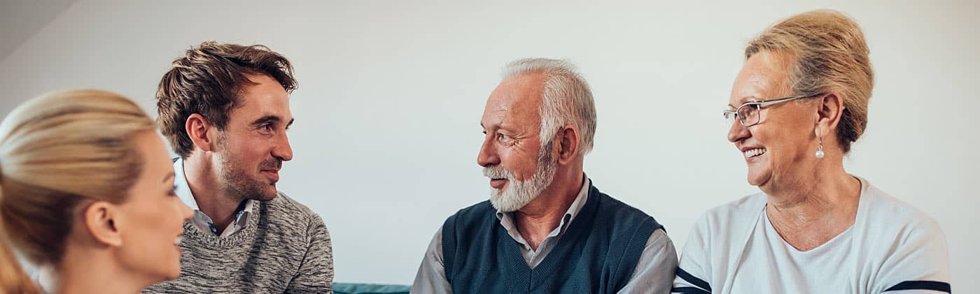 Multiple generations sitting on a couch discussing estate tax vs. inheritance tax 