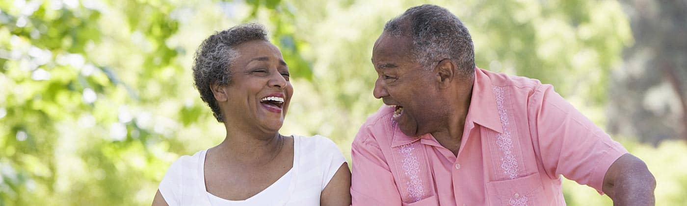 Older couple laughing as they ride bikes down a path: whole life insurance