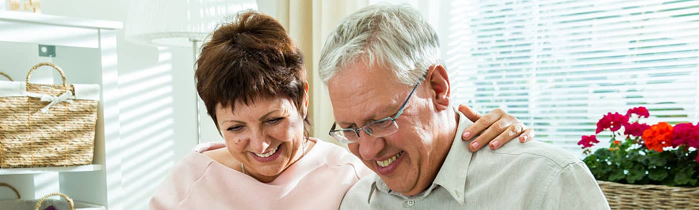 Older couple on laptop laughing and reading about why stocks split 