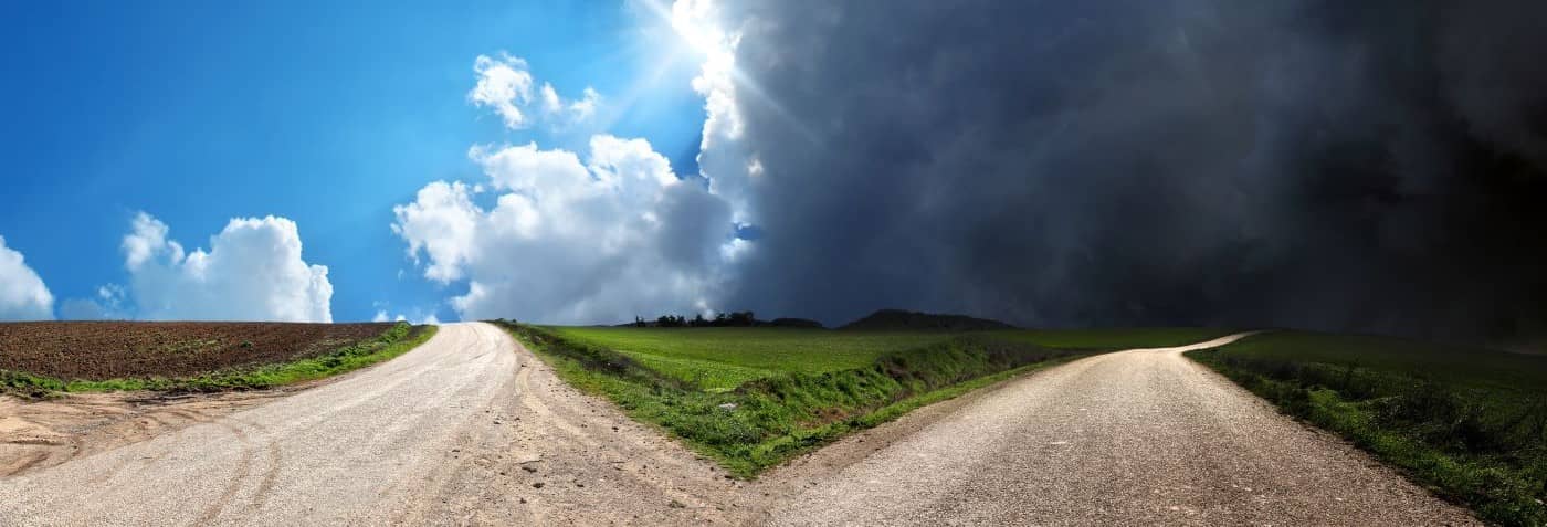 Empty forked road over conceptual dramatic sky.