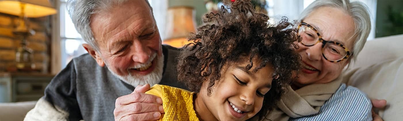 An older couple sits with their grandchild to discuss how grandparents can contribute to 529 plans.
