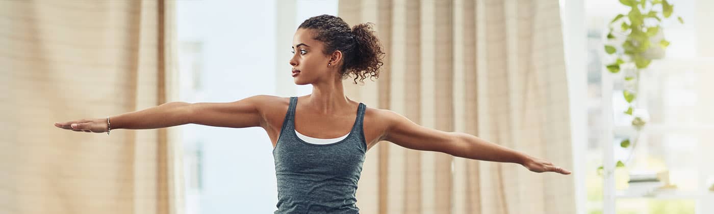 woman practices yoga pose outside as stress reduction to improve her long-term health