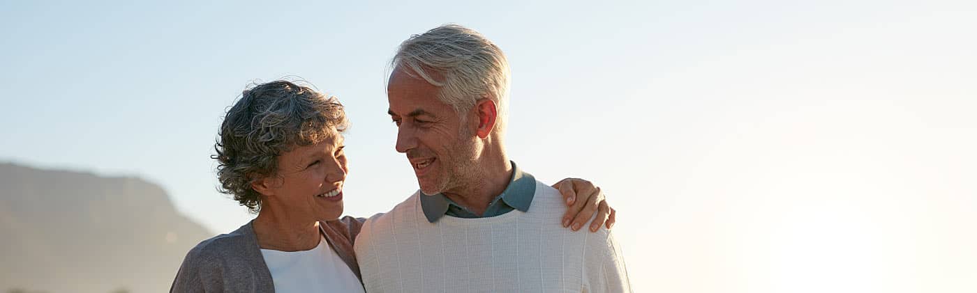 Retired couple walking on a beach and discussing their retirement checklist 