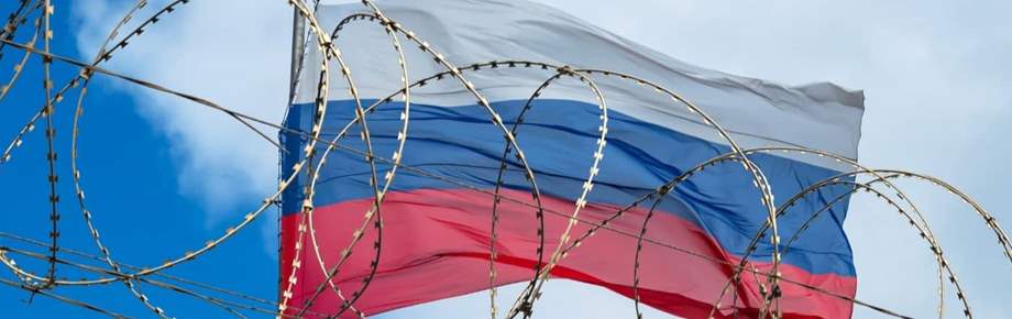 View of Russian flag behind barbed wire against cloudy sky.