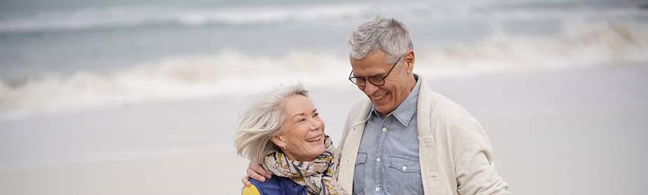 Senior couple enjoying a walk on the beach and discussing a possible lost 401(k) 