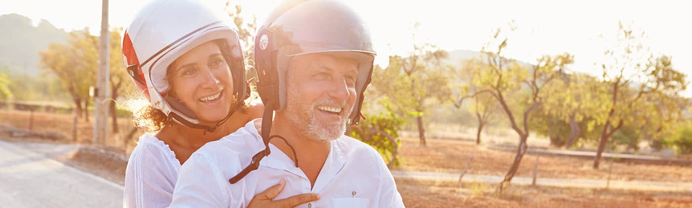 senior couple ride a motorscooter on a sunny day and recall common retirement myths they’ve learned