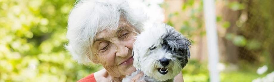 Senior woman holding her dog in a garden while estate planning for pets