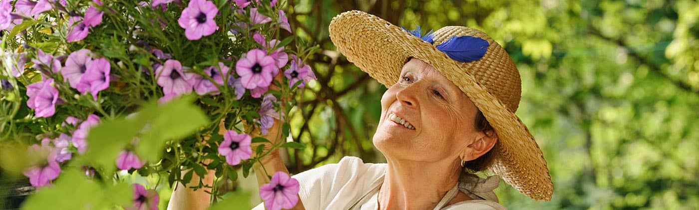 Senior woman smelling flowers on a tree while thinking about retirement catch-up contributions 