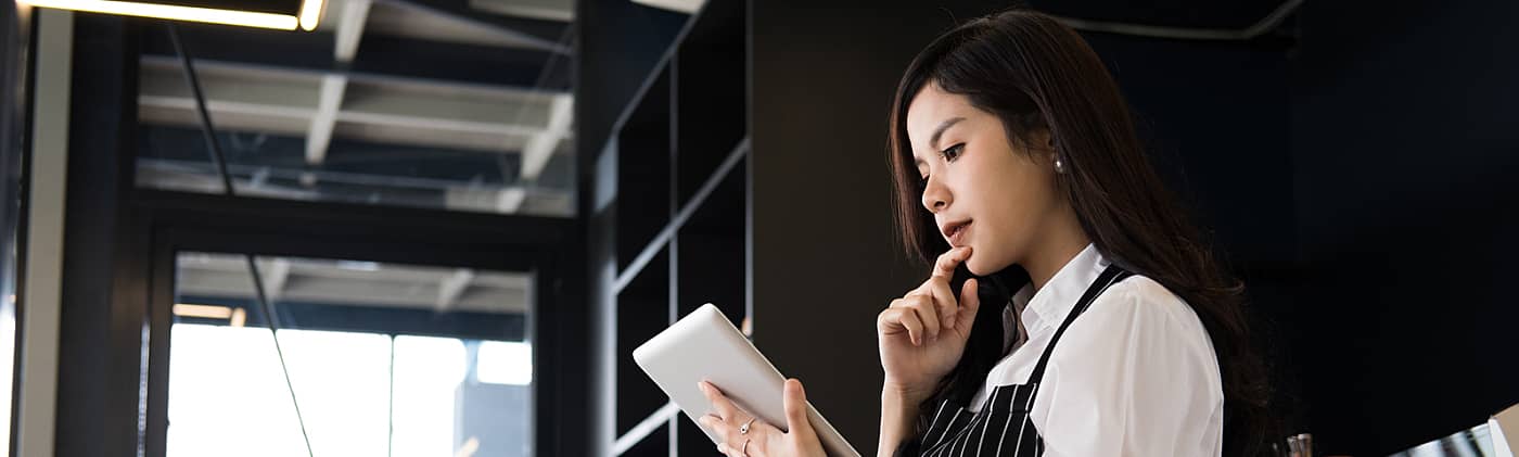 shop owner uses tablet and considers hiring independent contractors to reduce her small business taxes