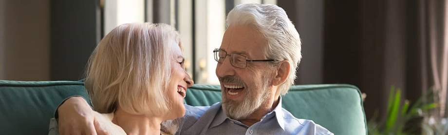 Smiling older couple looking at a tablet considering how much does a couple need to retire 